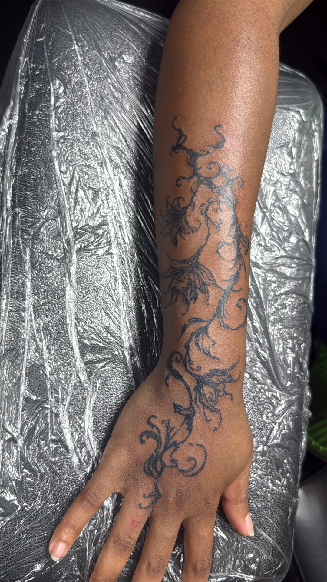 Fine line floral vine tattoo down the forearm and hand